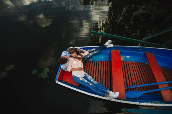 爱在船上的情侣。美丽的年轻夫妇拥抱和微笑，而躺在船上的顶视图. — 图库照片