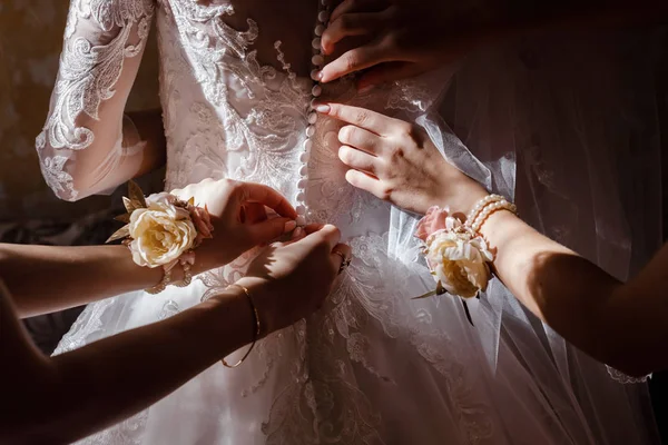 Dama de honra ajudando a noiva a prender espartilho e recebendo seu vestido, preparando a noiva de manhã para o dia do casamento. — Fotografia de Stock