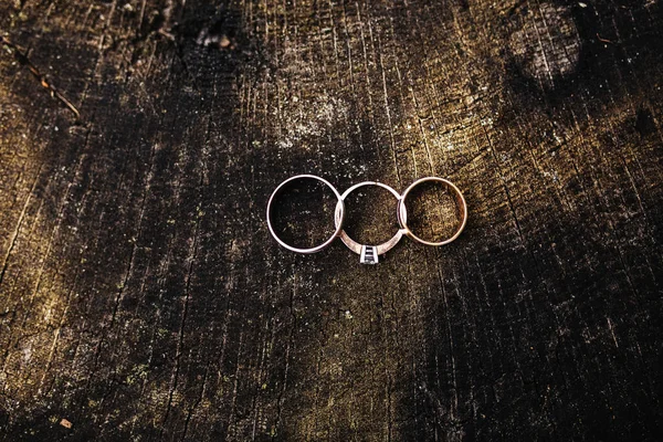 Os anéis de casamento bonitos encontram-se na superfície de madeira contra o fundo. Declaração de amor, saudação do Dia dos Namorados. Anéis de casamento. Detalhes do dia do casamento — Fotografia de Stock