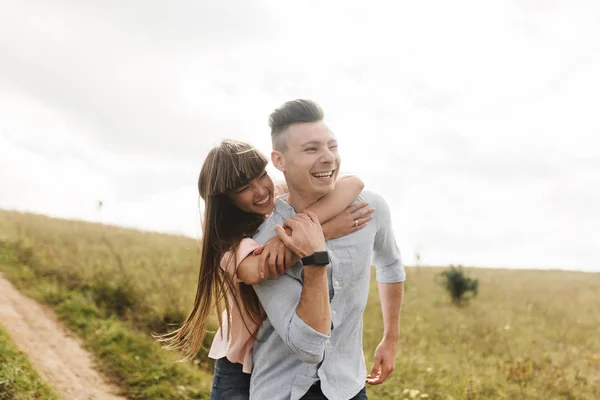 Feliz casal jovem abraçando e rindo ao ar livre. Amor e ternura. Conceito de estilo de vida — Fotografia de Stock