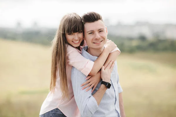 幸せな若いカップルは、屋外で抱きしめて笑っています。愛と優しさライフスタイルコンセプト — ストック写真