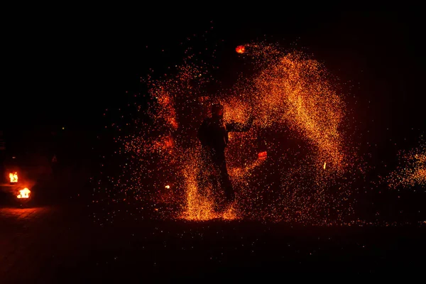 Fire show, dancing with flame, male master juggling with fireworks, performance outdoors, draws a fiery figure in the dark, bright sparks in the night. A man in a suit LED dances with fire. — Stock Photo, Image