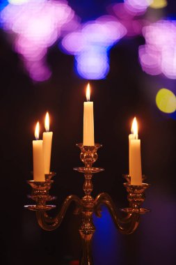 Evde ki koyu arka plana karşı bronz mumlar yakmak. Vintage tarzı. Sakin romantik bir atmosfer. Tasarım için yatay görüntü.