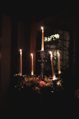 Evde ki koyu arka plana karşı bronz mumlar yakmak. Vintage tarzı. Sakin romantik bir atmosfer. Tasarım için yatay görüntü.