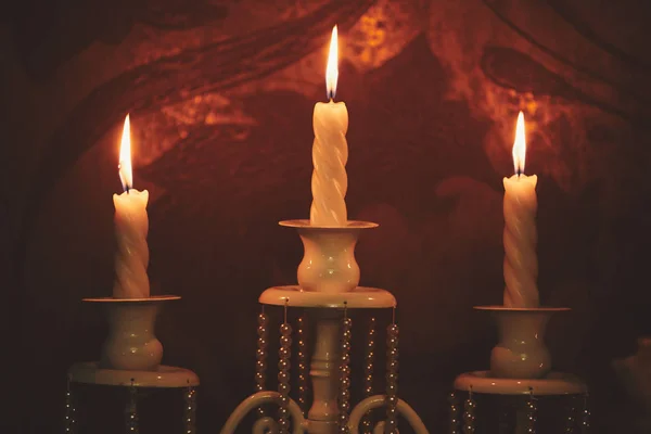 Brandende kaarsen op bronzen kandelaar tegen donkere achtergrond thuis. kaarsen in het interieur. Vintage stijl. Rustige romantische sfeer. Horizontale afbeelding voorontwerp. — Stockfoto