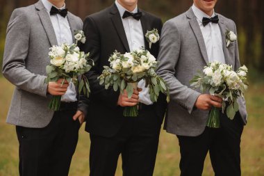 Şık damat gelin buketi tutuyor. Düğün buketi erkeğin ellerinde.