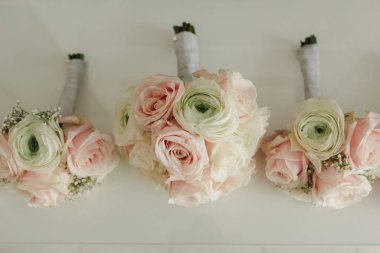 Gelin elinde, damadın ilik çiçeklerini beyaz güllerle, yeşil ve yeşilliklerle yakın tutuyor. Gelin Hazırlıkları. Düğün konsepti.