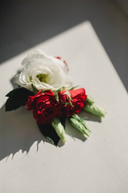 Gelin elinde, damadın ilik çiçeklerini beyaz güllerle, yeşil ve yeşilliklerle yakın tutuyor. Gelin Hazırlıkları. Düğün konsepti.