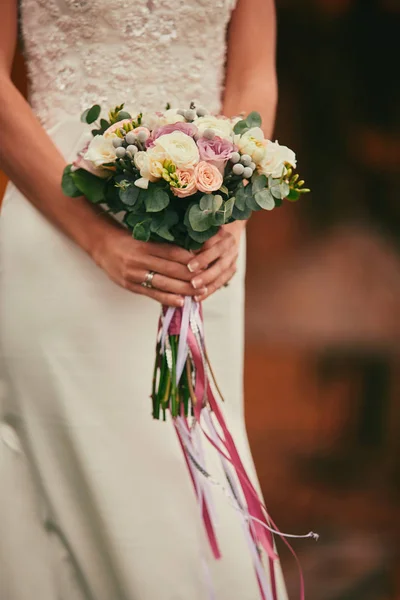 A noiva em um vestido de noiva elegante mantém um belo buquê de flores diferentes e folhas verdes. Tema do casamento — Fotografia de Stock