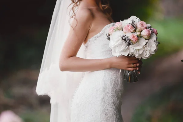 A noiva em um vestido de noiva elegante mantém um belo buquê de flores diferentes e folhas verdes. Tema do casamento — Fotografia de Stock