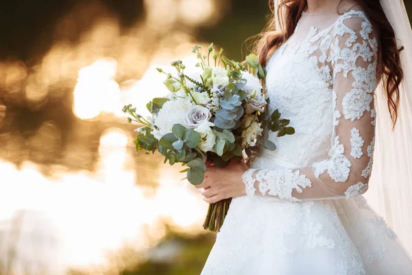 A noiva em um vestido de noiva elegante mantém um belo buquê de flores diferentes e folhas verdes. Tema do casamento — Fotografia de Stock