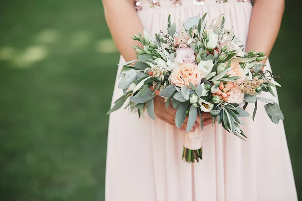 Hält die Braut in einem eleganten Brautkleid einen wunderschönen Strauß aus verschiedenen Blumen und grünen Blättern in der Hand. Hochzeitsthema — Stockfoto