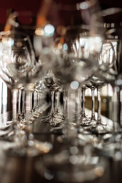 Leere Weingläser. schöne neue Gläser für Wein aus Glas stehen in geraden Reihen auf einem Holztisch in einem Restaurant. Selektiver Fokus — Stockfoto