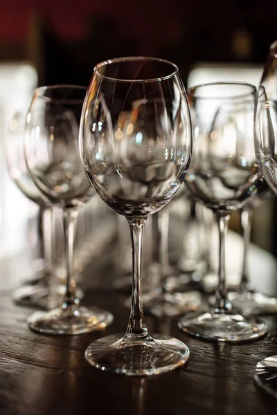 Leere Weingläser. schöne neue Gläser für Wein aus Glas stehen in geraden Reihen auf einem Holztisch in einem Restaurant. Selektiver Fokus — Stockfoto