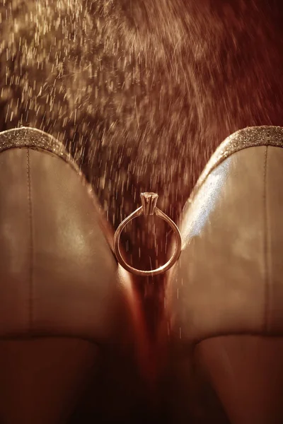 Ślubne buty i pierścionek z diamentem. Obrączka między beżowymi butami ślubnymi. Koncepcja akcesoriów ślubnych kobiet — Zdjęcie stockowe