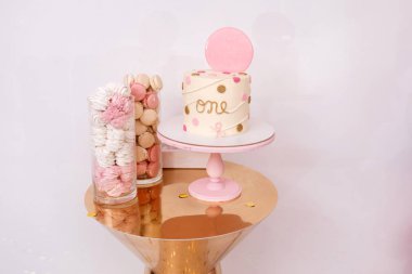 Bir yıllık çocuğun doğum günü için pembe dekor ile güzel doğum günü pastası. Macaroons ve marshmallows ile şeker çubuğu