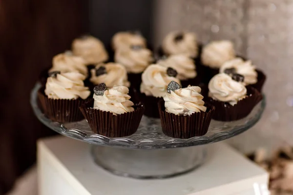 Pastelitos de chocolate. Magdalenas de chocolate caseras. El proceso de hacer magdalenas de chocolate caseras con crema batida y decoradas con chocolate. Enfoque selectivo. Concepto de barra de caramelo . — Foto de Stock