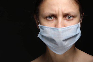 Coronavirus, siyah arka planda maskeli bir kız. Corona virüsünün salgını, hastalığı hakkında bir başlık. Salgın