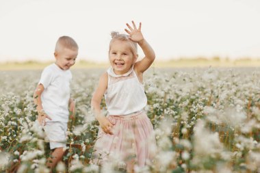 Mutlu çocuklar çiçek tarlasında eğleniyor. Mutlu çocukluk.