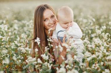 Mutlu çocuk ve annesi bir tarlada eğleniyor. Anne çocuğu kollarında tutuyor, ve çocuk sarılıyor. Anneler Günü. seçici odak