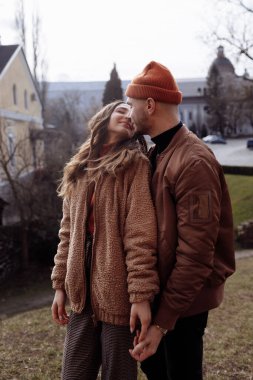 Şehirde öpüşen genç ve şık bir çift. Güzel, genç çiftlerin kucaklaşmalarının ve şehirde öpüşmelerinin açık havada çekilmiş romantik portresi. seçici odak