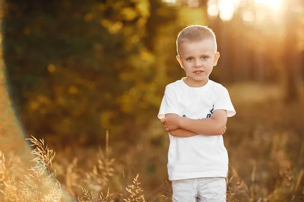 Retrato de niño pequeño con el pelo rubio y una camisa blanca cerca. retrato al atardecer —  Fotos de Stock
