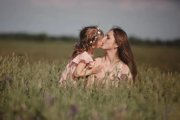 Família feliz: uma jovem mulher grávida bonita com sua filhinha fofa andando no campo de trigo em um dia ensolarado de verão. Relação entre pais e filhos. Natureza no país . — Fotografia de Stock