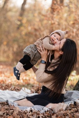 Genç güzel anne güneşli bir günde sonbahar parkında kızıyla oynuyor. Anneler Günü