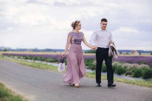 夏日阴天 年轻夫妇在薰衣草田附近散步 穿着华丽的紫色衣服 头戴花篮的女孩 — 图库照片