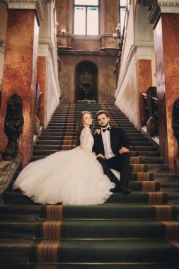 Güzel yeni evliler eski evin merdivenlerinde sarılıyorlar. Şık bir damat ve genç bir gelinin düğün portresi..