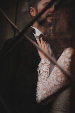 Genç ve şık yeni evliler eski ahşap kapının arkasında sarılıyorlar. düğün günü