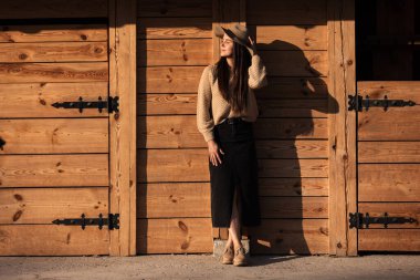 Güneşli bir sonbahar gününde, ahşap binanın yanındaki şapkalı güzel genç kadın..