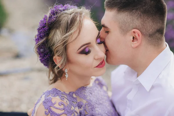 在夏日阴冷的日子里 年轻夫妇在薰衣草地里接吻 穿着华丽的紫色衣服和发型的女孩 — 图库照片