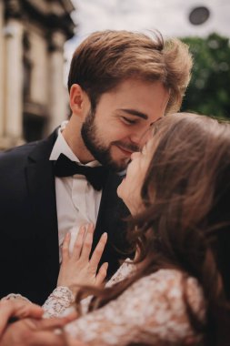 Eski Avrupa mahallesinde sarılıp öpüşen mutlu yeni evli çift, beyaz gelinlikli muhteşem gelin ve yakışıklı damat. düğün günü.