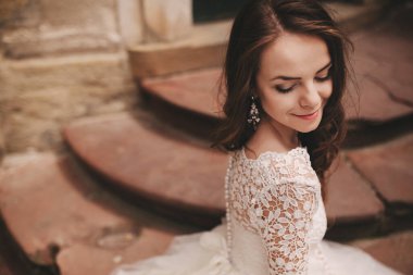 Eski Avrupa şehrinde beyaz bir gelinlik içinde uzun saçlı güzel bir gelinin portresi. Eski binanın yakınında bir kadın. düğün günü.