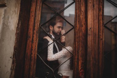 Genç ve şık yeni evliler eski ahşap kapının arkasında sarılıyorlar. düğün günü