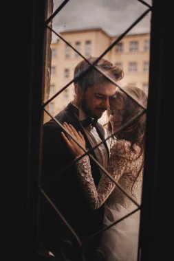 Genç ve şık yeni evliler eski ahşap kapının arkasında sarılıyorlar. düğün günü