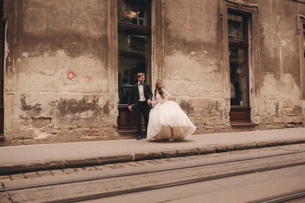 유럽의 구시가지를 산책하는 신랑과 드레스를 — 스톡 사진