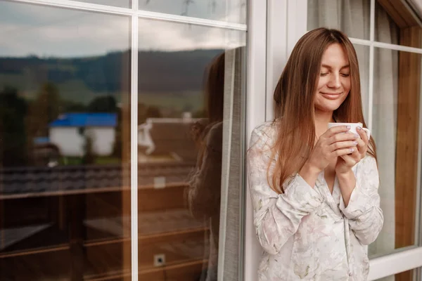 Junge Frau, die morgens nach dem Duschen auf dem Hotelbalkon steht. mit einer Tasse Kaffee oder Tee in der Hand. Außerhalb der Natur Wald und Berg — Stockfoto