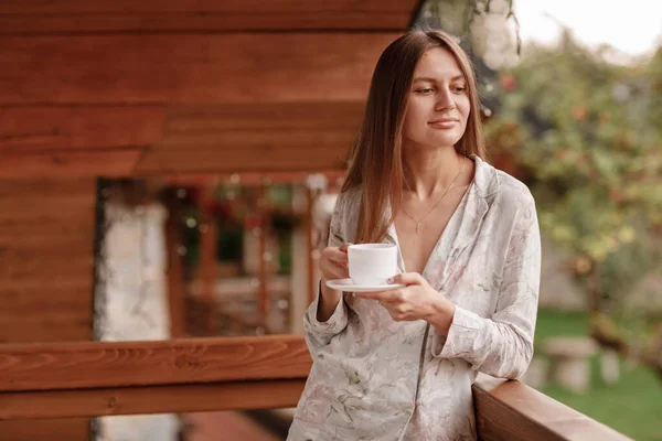 Junge Frau, die morgens nach dem Duschen auf dem Hotelbalkon steht. mit einer Tasse Kaffee oder Tee in der Hand. Außerhalb der Natur Wald und Berg — Stockfoto