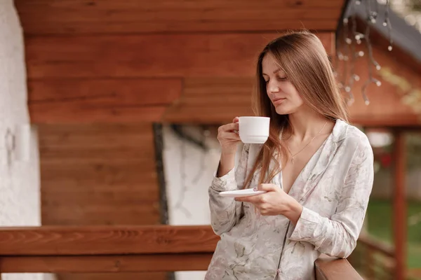 Junge Frau, die morgens nach dem Duschen auf dem Hotelbalkon steht. mit einer Tasse Kaffee oder Tee in der Hand. Außerhalb der Natur Wald und Berg — Stockfoto