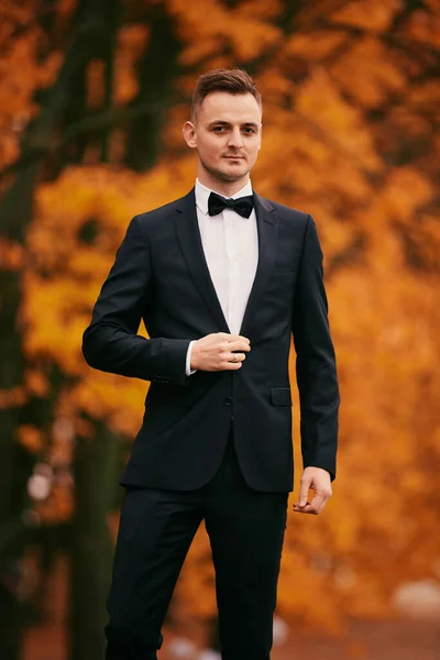結婚式の日の秋の公園の黒いスーツを着たスタイリッシュな若い新郎 — ストック写真
