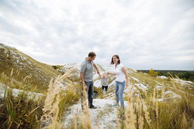 Anne, baba kızına dağlarda sarılıyor ve doğanın tadını çıkarıyor. Genç bir aile tatilde, dışarıda birlikte vakit geçiriyor. Aile yaz tatili kavramı. Anneler günü, babalar günü, bebekler günü..
