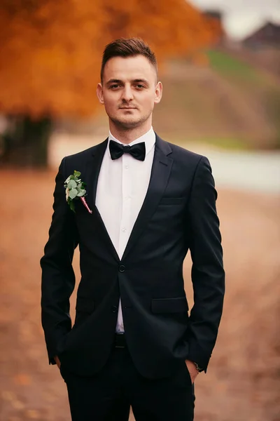 結婚式の日の秋の公園の黒いスーツを着たスタイリッシュな若い新郎 — ストック写真