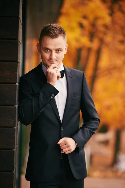 婚礼当天 穿着黑色西服的时尚年轻新郎在秋天的公园里 — 图库照片