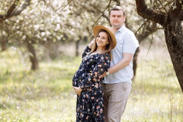Familia Feliz Esposa Embarazada Marido Abrazan Floreciente Parque Primavera Enfoque — Foto de Stock