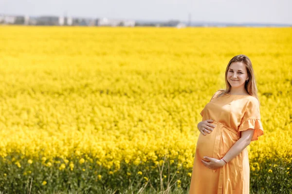 Junge Schwangere Frau Gelben Rapsfeldern Hält Ihren Bauch Und Trägt — Stockfoto