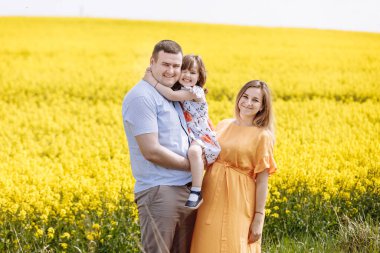Sarı çiçek tarlalarının arasında mutlu bir aile. Aile uykusu. Hamile anne, baba ve küçük kız sarı Colza 'nın arasında dinleniyorlar.