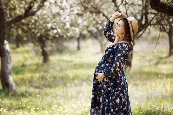 Piękna Ciężarna Kobieta Słomkowym Kapeluszu Wiosennym Parku Kwitnącym Oczekująca Matka — Zdjęcie stockowe