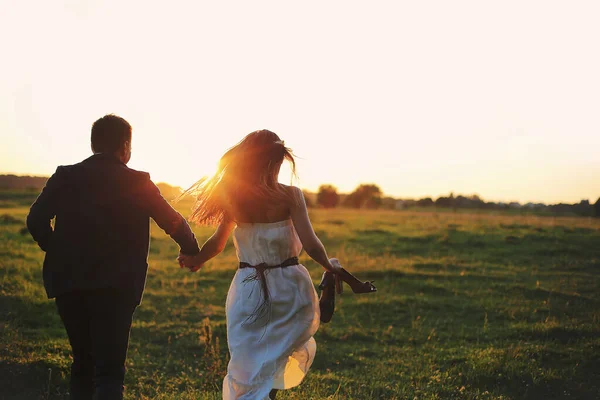 这对年轻漂亮的夫妇正在玩得很开心 夏天在田里跑来跑去 日落时的浪漫照片 爱情故事 — 图库照片